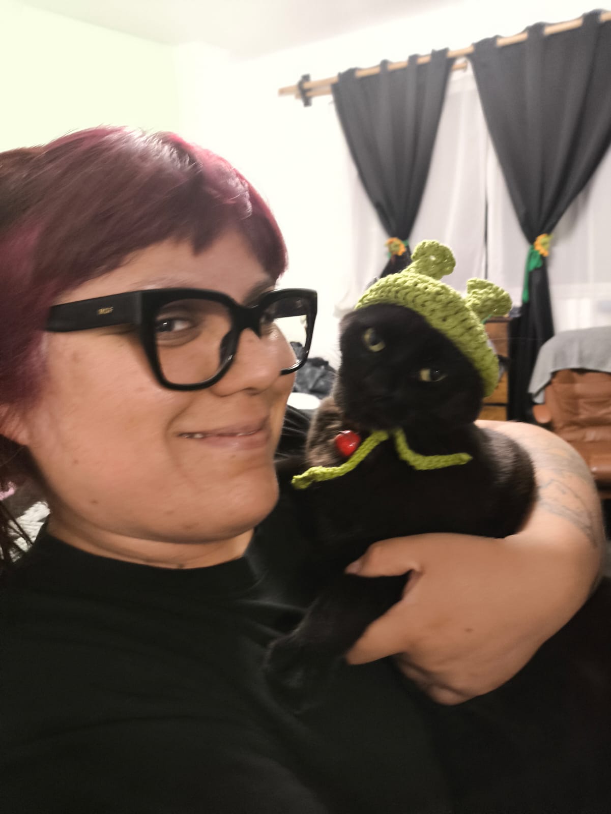 Ana Belen cargando a Borlanda, la gatita negra, con un gorrito verde de Shrek